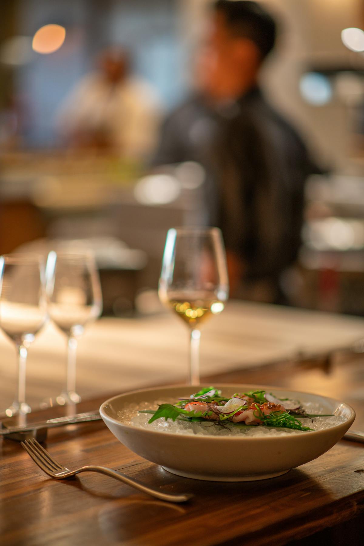 a bowl of food and glasses of wine on a table